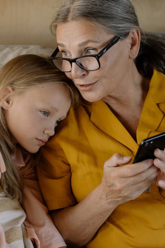 Senior woman and young girl enjoying time together, bonding over a smartphone indoors.